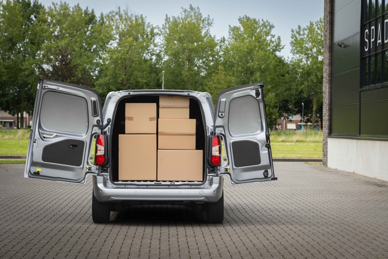 A heavy cargo is unloaded from a Proace City with its rear doors open 